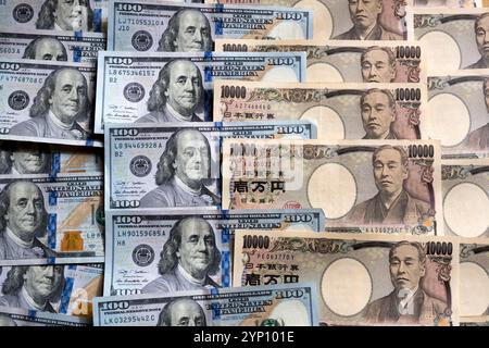 Muster von US-Dollar und japanischen Yen in großen 100- und 10.000-Yen-Banknoten, die ein Hintergrundbild der beiden Währungen erzeugen. Stockfoto