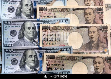 Muster von US-Dollar und japanischen Yen in großen 100- und 10.000-Yen-Banknoten, die ein Hintergrundbild der beiden Währungen erzeugen. Stockfoto