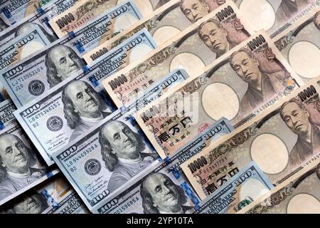 Muster von US-Dollar und japanischen Yen in großen 100- und 10.000-Yen-Banknoten, die ein Hintergrundbild der beiden Währungen erzeugen. Stockfoto