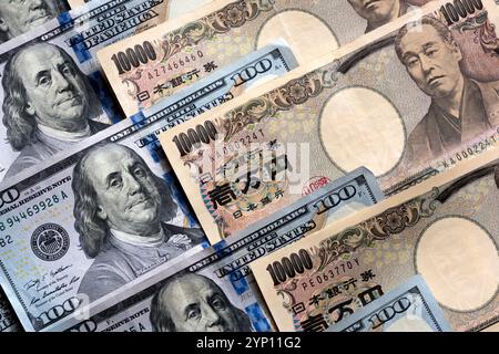 Muster von US-Dollar und japanischen Yen in großen 100- und 10.000-Yen-Banknoten, die ein Hintergrundbild der beiden Währungen erzeugen. Stockfoto
