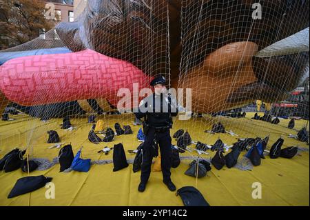 New York, USA. November 2024. Ein Offizier der NYPD steht neben Gabby aus Gabbys Dollhouse Ballon (neu 2024), der während der jährlichen Ballonaufblasung am Vorabend der Macy's Thanksgiving Day Parade 2024, New York, NY, 27. November 2024, unter einem Netz gehalten wird. Tausende von New Yorkern und Touristen haben die Chance, mehr als 30 Ballons zu sehen, während sie sich auf die 98. Ausgabe der Parade am 28. November vorbereiteten. (Foto: Anthony Behar/SIPA USA) Credit: SIPA USA/Alamy Live News Stockfoto