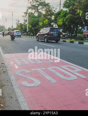 Balikpapan, Indonesien - 3. September 2024. Ein Schild mit Bushaltestelle auf der Straße, auf dem der Verkehr im Hintergrund steht. Stockfoto