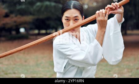 Holzschwert, japanische Frau und Outdoor in Training, Sport oder Sport für Kampfkunst. Weibliche Person, Waffe und Erbe für Herausforderung und Kampf Stockfoto