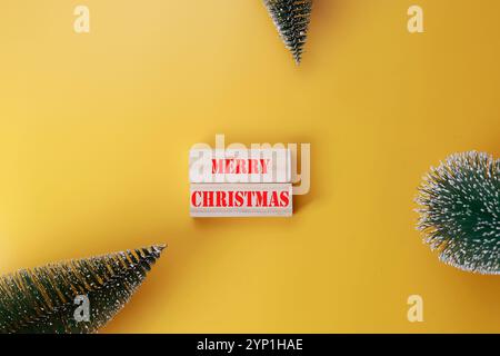 Frohe Weihnachten Symbol auf Holzblöcken mit den Worten Frohe Weihnachten. Schöner gelber Hintergrund. Stockfoto