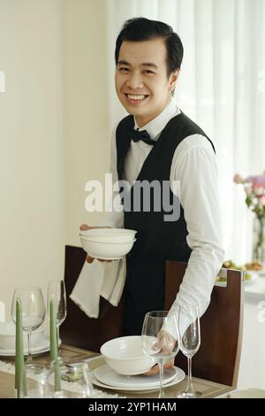Lächelnder Kellner, der den Tisch im Restaurant aufstellte Stockfoto