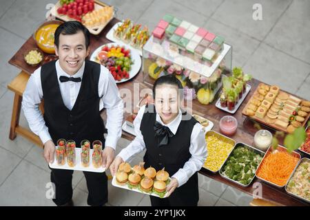 Lächelnde Köche präsentieren Teller mit Vorspeisen Stockfoto