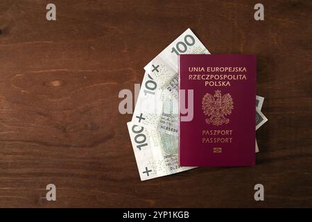 Pass "Republik Polen der Europäischen Union" und 100 PLN polnische Banknoten auf Holztisch Stockfoto