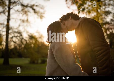 Porträt eines glücklichen Liebespaares im Park bei Sonnenuntergang. Mann und Frau küssen sich bei Sonnenuntergang. Stockfoto