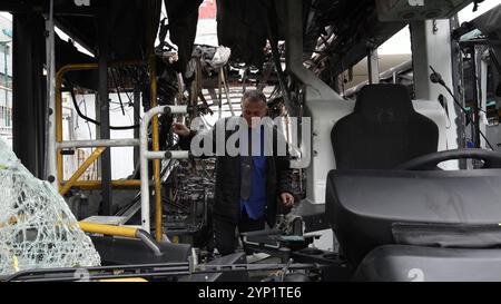 KIRYAT SHMONA, ISRAEL - 27. NOVEMBER: Ein Busfahrer inspiziert die Schäden in einem ausgebrannten Bus an der Stelle, an der ein Raketenangriff aus dem Libanon nur wenige Stunden vor dem Waffenstillstand zwischen Israel und Hisbollah in 2024 Kiryat Shmona nahe der Grenze zum Libanon über Nacht auf eine Bushaltestelle traf. Stockfoto