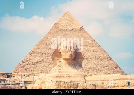 Nahaufnahme des Gesichts der Großen Sphinx mit Pyramide im Hintergrund an einem schönen bewölkten blauen Himmel in Gizeh, Kairo, Ägypten. Vorderansicht Stockfoto