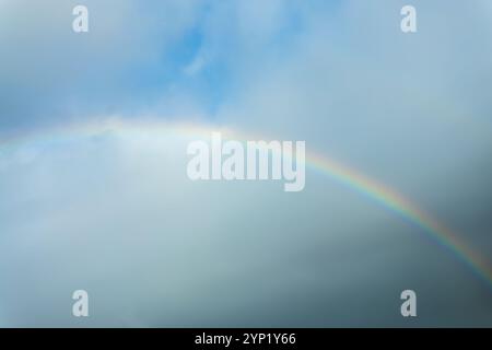 Echtes Foto eines Regenbogens am Himmel mit Wolken und blauem Himmel Stockfoto