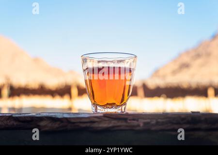 arabischer Tee im beduinenzelt. Tee in Glas steht auf einem Holztisch vor dem Hintergrund verlassener Häuser. Stockfoto