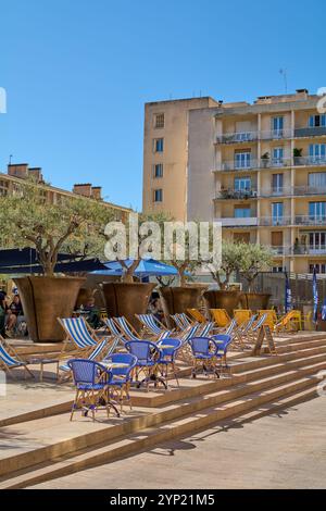 Marseille. Frankreich - 27. November 2024: Ein lebendiges Café im Freien in Marseille mit großen Pflanzgefäßen mit Bäumen, Liegestühlen und Tischen im Schatten, sur Stockfoto