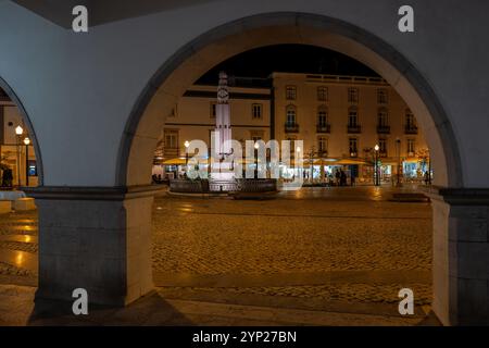 Der mit Kopfsteinpflaster gepflasterte Hauptplatz República von Tavira bei Nacht durch einen Bogen, Tavira, Algarve, Portugal Stockfoto