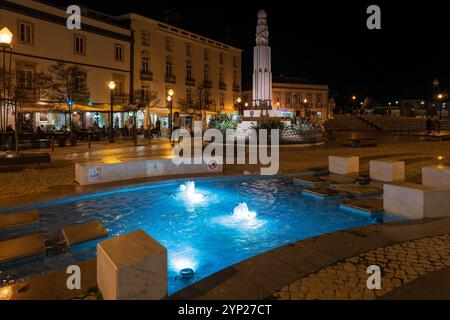 Hauptplatz mit Kopfsteinpflaster (Praca da República) bei Nacht mit beleuchtetem Brunnen, Tavira, Algarve, Portugal Stockfoto