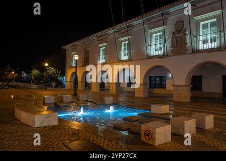 Hauptplatz mit Kopfsteinpflaster (Praca da República) bei Nacht mit beleuchtetem Brunnen, Tavira, Algarve, Portugal Stockfoto