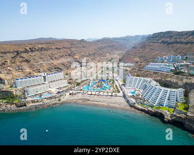 Ein atemberaubender Blick auf Gran Canarias Klippen-Resorts mit luxuriösen Unterkünften, einem lebhaften Wasserpark und einem Sandstrand entlang der Küste Stockfoto