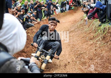 Bandung, Indonesien. November 2024. Ein Teilnehmer fährt mit einem traditionellen Holzwagen, bekannt als Kadaplak, bergab bei Cisurupan in Bandung, West Java Province, Indonesien, 28. November 2024. Quelle: Septianjar Muharam/Xinhua/Alamy Live News Stockfoto