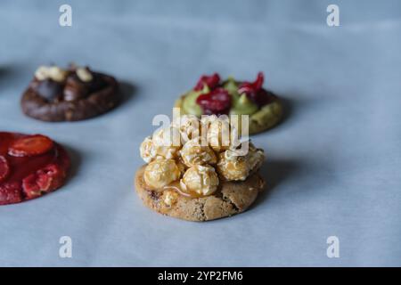 Hausgemachter amerikanischer Schokoladen-Chip-Keks mit Karamell-Popcorn und anderen dekorierten Keksen auf dem Hintergrund. Stockfoto