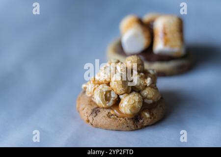 Hausgemachter amerikanischer Schokoladen-Chip-Keks mit Karamell-Popcorn und anderen dekorierten Keksen auf dem Hintergrund. Stockfoto