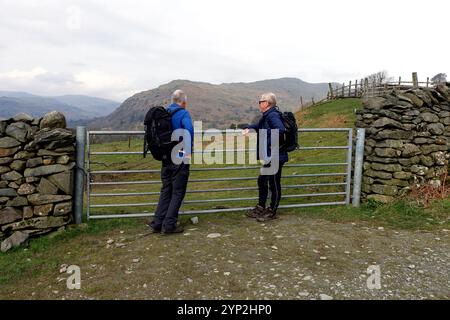 Zwei Männer stehen am Iron Gate und sehen die Wainwrights „NAB Scar“ und „Heron Pike from the Track to „Low Pike“ aus Ambleside, Lake District, Großbritannien. Stockfoto