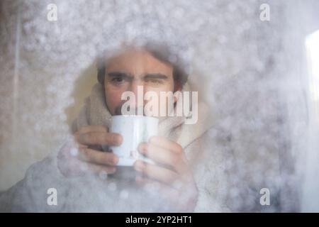 23. November 2024: Ein ruhiger Moment vor einer eisigen Fensterscheibe mit einer heißen Tasse Tee - ein symbolisches Bild für steigende Heizkosten, Energieeinsparung und die Herausforderungen kalter Wintertage. *** Ein stiller Moment vor einer vereisten Fensterscheibe mit einer heißen Tasse Tee ein Symbolbild für steigende Heizkosten, Energiesparen und die Herausforderungen kalter Wintertage. Stockfoto