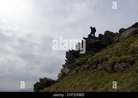 Lone man (Wanderer) auf Rock Crags in der Nähe des Gipfels des Wainwright „High Pike“ im Lake District National Park, Cumbria, England, Großbritannien. Stockfoto