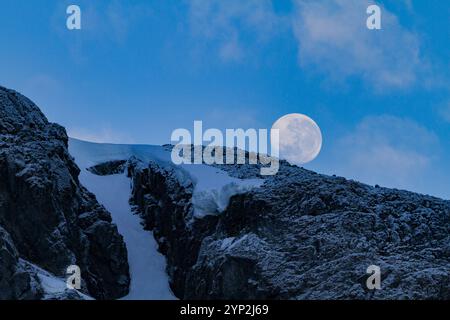 Blick auf den fast Vollmond, der über schneebedeckten Bergen auf der Antarktischen Halbinsel, Antarktis und Polarregionen aufsteigt Stockfoto