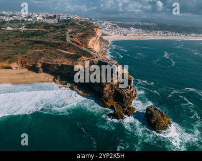 Blick auf Touristen aus der Vogelperspektive des historischen Leuchtturms Sao Miguel Arcanjo mit Blick auf die atemberaubende Küste von Nazare mit riesigen Wellen Stockfoto