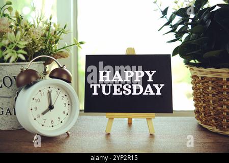 Happy Tuesday Text auf Papierkarte mit Ealsel auf hölzernem Hintergrund Stockfoto