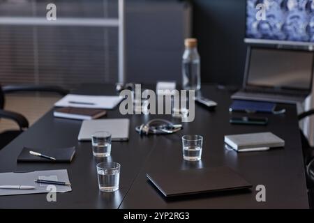 Hintergrundaufnahme eines geschlossenen Laptops, der auf dem Besprechungstisch mit Wassergläsern für Seminarteilnehmer im medizinischen Büro, Kopierraum platziert wurde Stockfoto