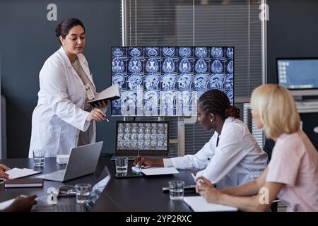 Professionelle Radiologin aus dem Nahen Osten, die MRT-Bilder des Gehirns von Patienten auf dem Bildschirm zeigt und Forschungsergebnisse an Hochschulen vorstellt Stockfoto