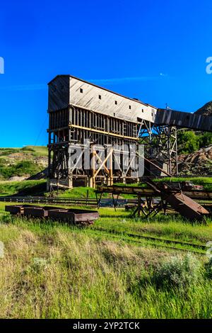 Ein großes Gebäude mit vielen Fenstern und einem Metalldach. Das Gebäude ist von Gras und Bäumen umgeben Stockfoto