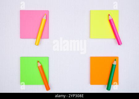 Leere Haftnotizen mit Farbstiften auf weißer Leinwand. Bunte Notizblöcke. Stockfoto