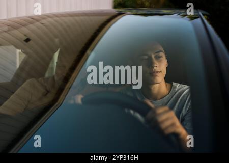 Nachdenklicher junger Mann sitzt mit Vater im Auto, durch die Windschutzscheibe gesehen Stockfoto