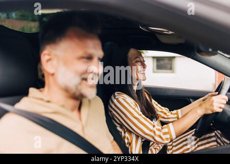 Glücklicher Mann, der mit einer Frau sitzt, die Auto fährt Stockfoto