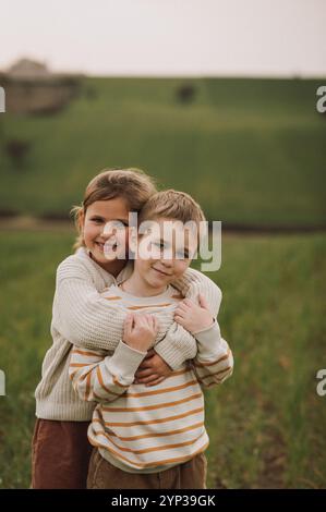 Junge und Mädchen rennen auf einem Feld und versuchen, einen Drachen zu fangen. Sie lächeln, lachen und umarmen sich Stockfoto