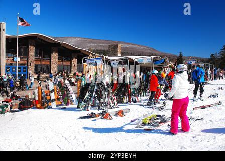 Eine junge Frau zieht ihre Ski für eine Mittagspause in einem Skigebiet an einem Wintertag ab Stockfoto