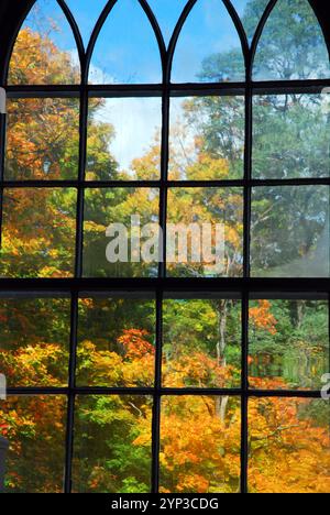 Ein Kirchenfenster bietet einen herrlichen Blick auf die Herbstfarben durch den Rahmen in New England Stockfoto