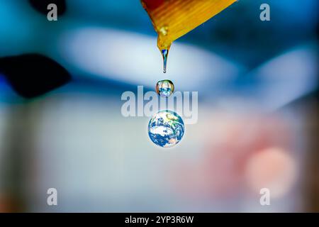 Ein Tropfen Wasser, das aus einem Rohr fällt, mit einer Reflexion der Erde. Dieses Bild symbolisiert die Fragilität unseres Planeten und die Verflechtungen aller Stockfoto