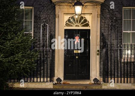 London, Großbritannien. November 2024. Der Welt-AIDS-Tag ist am 1. Dezember, und die Downing Street bereitet sich darauf vor, den Tag mit einem roten Band an der Tür Nr. 10 und einem Empfang später heute Abend zu feiern. Quelle: Imageplotter/Alamy Live News Stockfoto