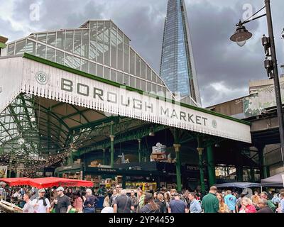 London, England, UK - 3. Juli 2024: Menschen vor dem Eingang zum Borough Market im Zentrum von London. Im Hintergrund ist der Shard. Stockfoto