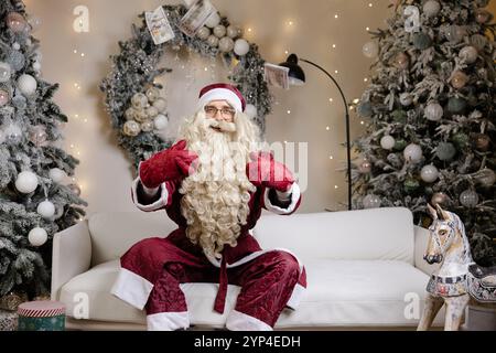 Der Weihnachtsmann sitzt in einem wunderschön eingerichteten Zimmer und hält Geld in der Hand. Stockfoto