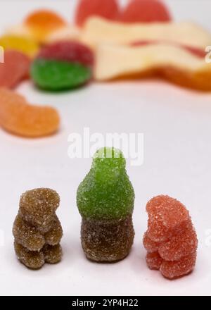 Traurige Gummibären, die auf eine Gelee-Cola-Flasche auf weißem Hintergrund schauen Stockfoto