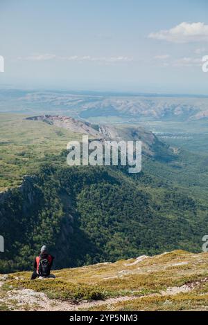Mann macht Fotos von der Aussicht auf den Wald von der Bergspitze auf der Wanderung Stockfoto