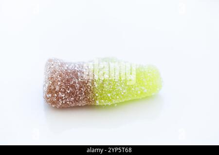 Detailstudio, aufgenommen von oben aus einer Cola-Flasche aus Jelly Beans mit Zucker darauf. Es ist auf einem sauberen weißen Hintergrund. Konzept von süßem Essen, süß Stockfoto