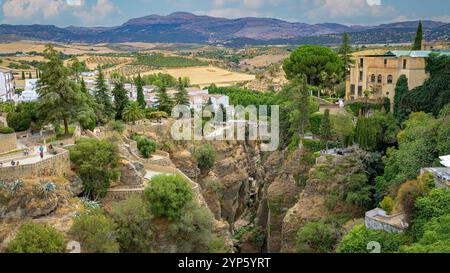 Puente Viejo Brücke in Ronda, mit mehreren Terrassen und Aussichtspunkten, mit Feldern und Bergen im Hintergrund Stockfoto