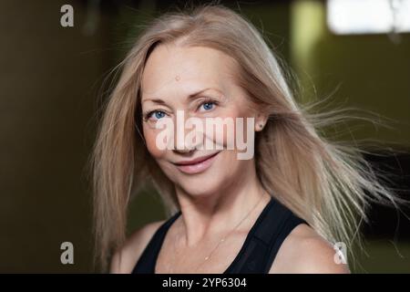 Porträt einer selbstbewussten blonden Frau mit blauen Augen, die in die Kamera blickt, einer Frau mittleren Alters, die vor der Kamera posiert, mit einem Lächeln im Gesicht, Nahaufnahme Stockfoto
