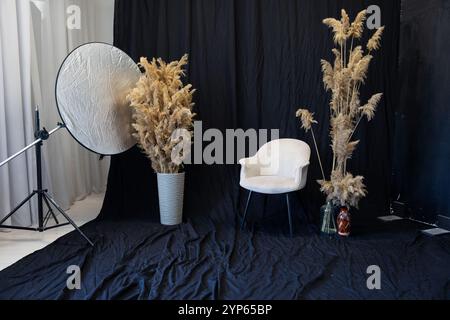 Stuhl mit Körben mit getrockneten Blumen auf schwarzem Hintergrund des Fotostudios Stockfoto