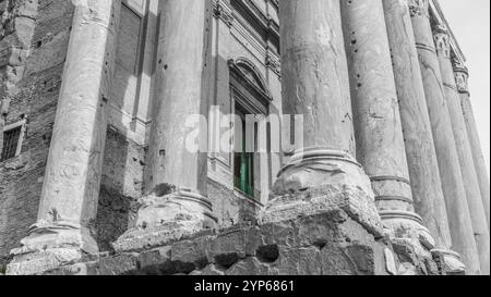 Außenansicht der grünen Tür zum Tempel des Antoninus und Faustina: Schatten und graue Details Stockfoto